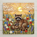 Stained glass style ceramic art tile of a mother raccoon and baby raccoon in a wildflower meadow of poppies daisies and lavender at sunrise, woodland nursery and baby shower decor.