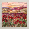 This stained-glass-inspired ceramic tile captures a glowing field of red poppies under a warm sunset sky. A perfect floral gift or wall accent.