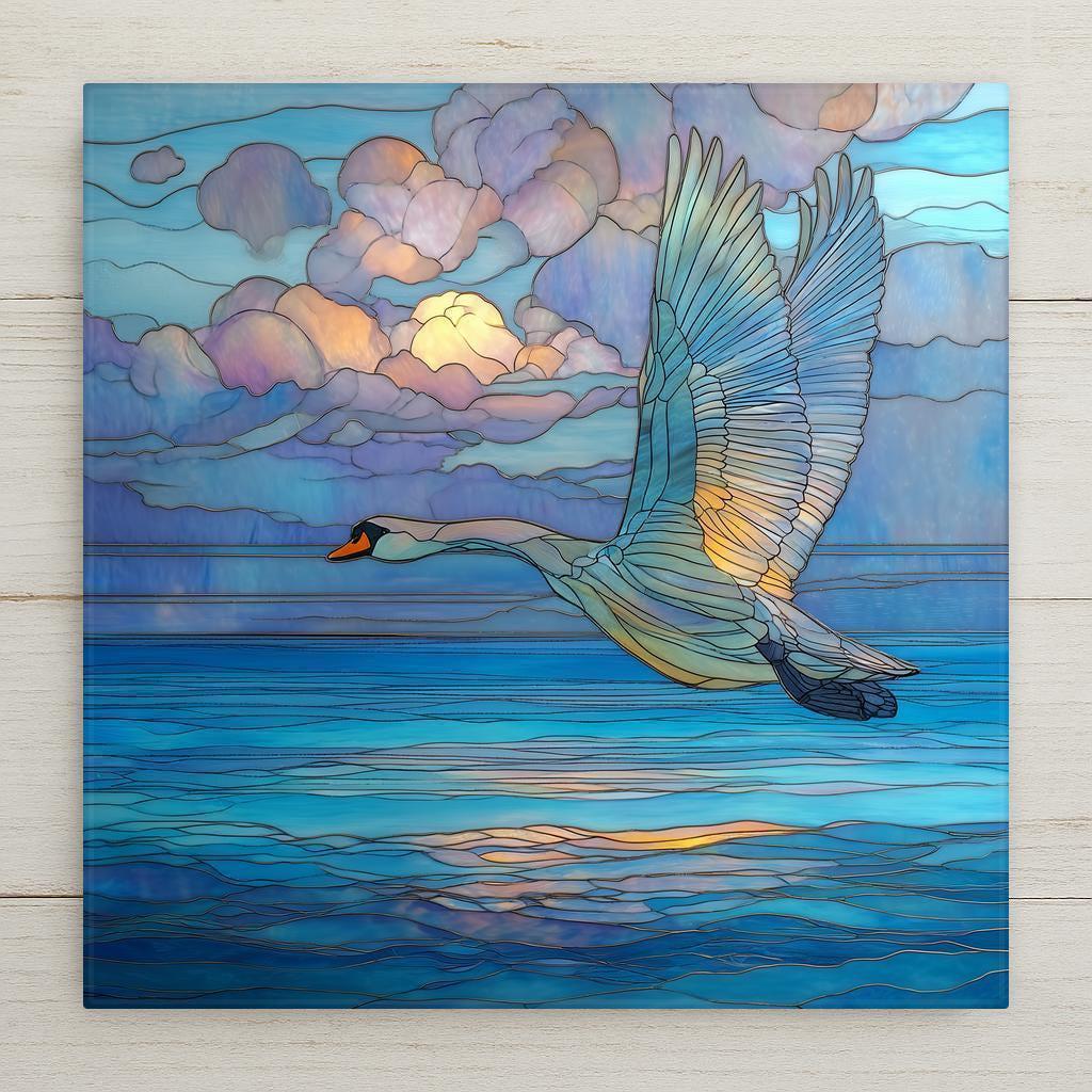 Stained glass style swan in flight ceramic tile with wings fully extended over deep cobalt and teal water at golden hour, warm gold and amber light catching the spread feathers, a vivid wildlife bird and nature lover gift.