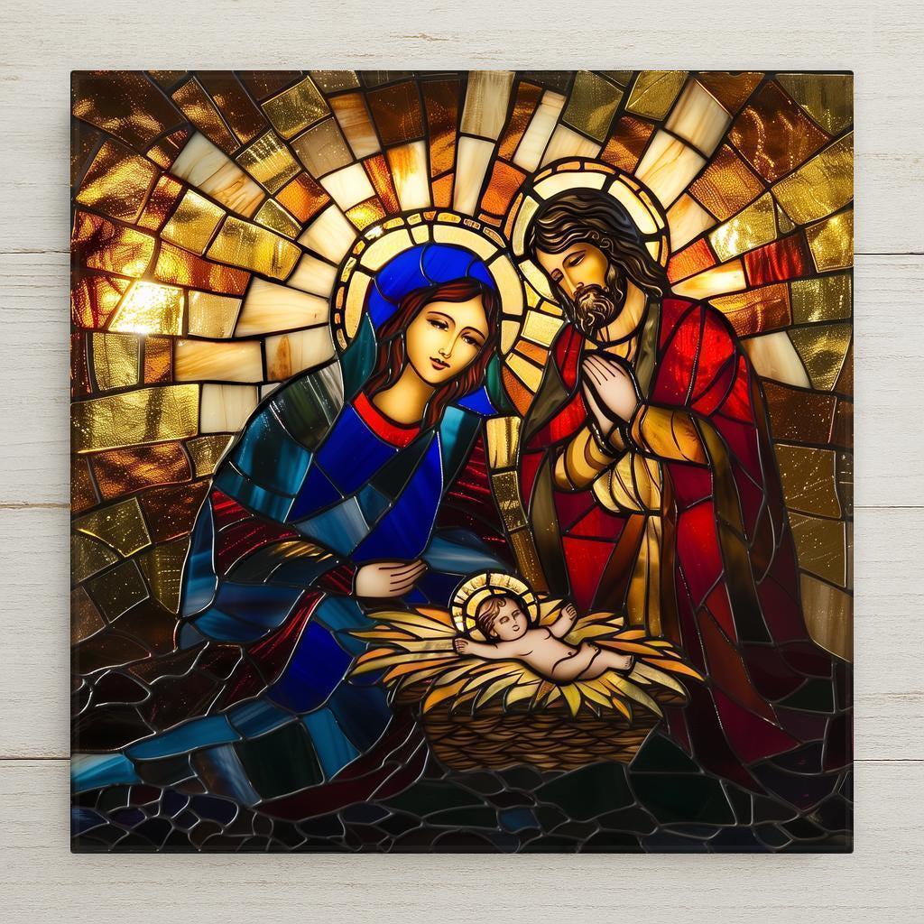 A stained-glass-style nativity: Mary in a blue robe and Joseph in red, both haloed in gold, bow over the infant Jesus asleep in a straw manger, set against a radiant golden sunburst of mosaic glass.