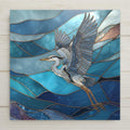 Great blue heron in flight over layered turquoise and deep blue ocean waves in stained glass style, coastal ceramic tile wall art.