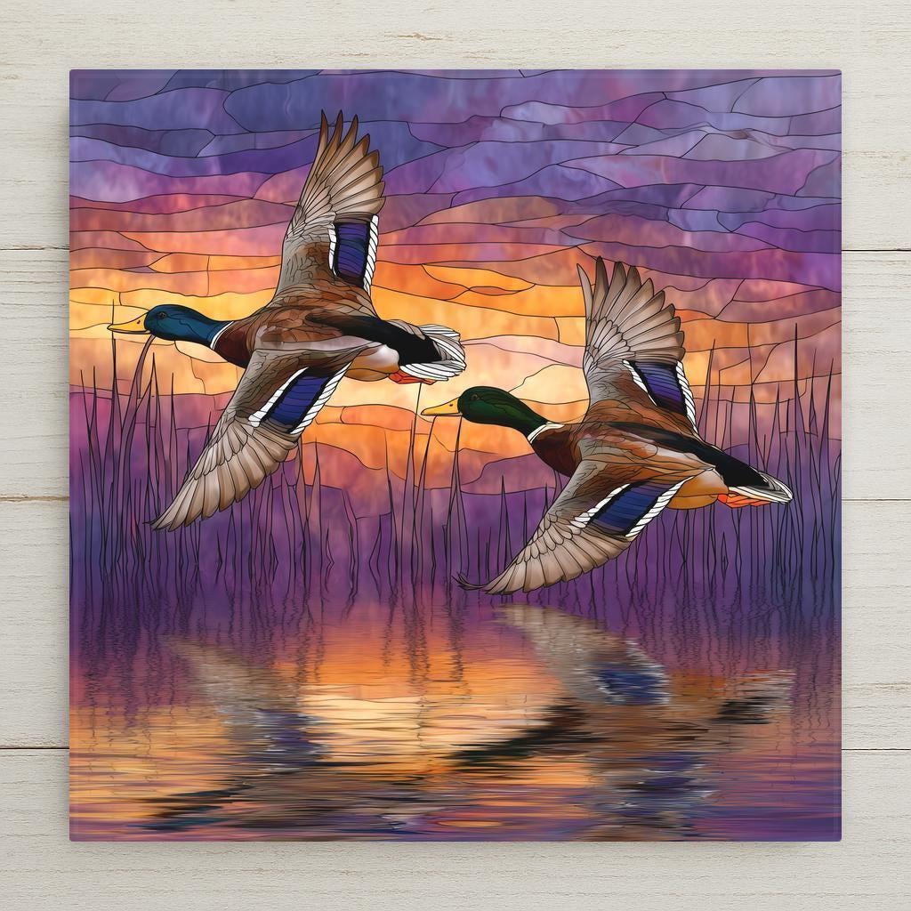 Stained glass style ceramic tile featuring two mallard ducks flying over a lake at sunrise with purple and orange sky reflections.