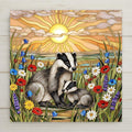 Stained glass style ceramic art tile of a mother badger and baby badger in a wildflower meadow of poppies daisies and lavender at sunrise, woodland nursery and baby shower decor.