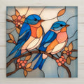 Stained glass-style ceramic tile artwork featuring two bluebirds perched together on a flowering branch. Soft blue, peach, and cream tones create a peaceful, symbolic nature scene printed on a smooth ceramic tile.