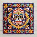 Hand-painted Talavera style ceramic art tile of a colorful Day of the Dead sugar skull surrounded by dense Mexican folk art florals in cobalt blue, red, gold, and green — a Dia de los Muertos decoration.