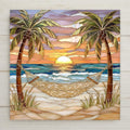 Stained-glass style ceramic tile featuring a tropical beach sunset with two palm trees and a hammock overlooking teal ocean waves. Coral and gold sky reflects on the water, creating a peaceful coastal scene. Beach house wall decor design inspired by seaside relaxation.