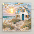 Stained glass style coastal cottage ceramic tile featuring a white beach house with blue door at sunset, golden sun reflecting over ocean waves, sandy path through dune grass leading to cottage. Coastal wall art for beach house decor, seaside home styling, and ocean-inspired interiors.