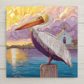 Stained glass style pelican ceramic tile with a majestic brown pelican perched on a harbor piling at golden sunset, deep cobalt and teal harbor water and warm amber light, sailboats behind, a vivid coastal bird and pelican lover gift.