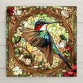 Add a splash of timeless elegance to your space with this Alphonse Mucha-inspired hummingbird tile. Designed to emulate the flowing lines and stained-glass texture of Art Nouveau, this ceramic piece showcases a ruby-throated hummingbird poised among rich foliage and blossoms. Whether you're decorating a cozy reading nook, your kitchen backsplash, or looking for a unique wildlife gift, this tile offers beauty and utility.
