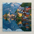 Stylized ceramic art tile of the Austrian alpine village of Hallstatt, with its church spire and colorful lakeside houses reflected in a calm lake beneath the mountains — European travel wall decor.
