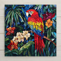 Stained glass style scarlet macaw ceramic tile with crimson and gold parrot perched among deep cobalt teal jungle and cascading tropical flowers, a vivid parrot lover tropical bird gift.