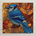 Stained glass style ceramic tile of a blue jay perched on an oak branch with an acorn, vivid cobalt and sky blue plumage with black necklace markings, the geometric leading lines picking out every barred feather detail against an autumn gold sky.