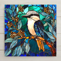 Stained glass style kookaburra ceramic tile with a warm amber and gold kookaburra perched on a eucalyptus branch against deep cobalt teal Australian bush, a vivid Australia bird lover gift.