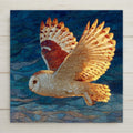 Stained glass style ceramic tile of a Snowy Owl in flight against a dramatic Arctic winter sky, white and gold wing feathers spread wide, rendered in jewel-tone whites, creams, and soft gold with luminous silver and copper leaded lines against a deep cobalt and midnight blue background.