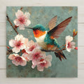 Ceramic art tile depicting a rufous hummingbird with copper and green plumage hovering amid pale pink cherry blossom clusters in fine art oil painting style with gold leaf accents