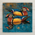 Stained glass mosaic style ceramic tile of two male Wood Ducks in full iridescent breeding plumage swimming side by side on rippling teal-blue water, both with their reflections below, rendered in jewel-tone teals, emerald greens, chestnut reds, and golden amber with intricate mosaic leaded lines.