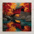 Stained glass style ceramic tile of a classic red covered bridge spanning a rocky New England stream in autumn, surrounded by blazing red and gold maple trees, rendered in jewel-tone autumn reds, golds, and amber with luminous copper leaded lines.