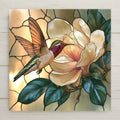 Stained glass style ceramic tile of a hummingbird hovering at a large white magnolia blossom with a pink blush and glossy green leaves on warm ivory glass