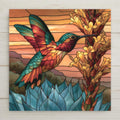 Stained glass style ceramic tile of an emerald hummingbird hovering at the golden blooms of a tall agave stalk against a warm desert sky