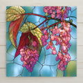 Stained glass style ceramic tile of an angel wing begonia with polka dot leaves red undersides and hanging pink blossom clusters against blue glass panes