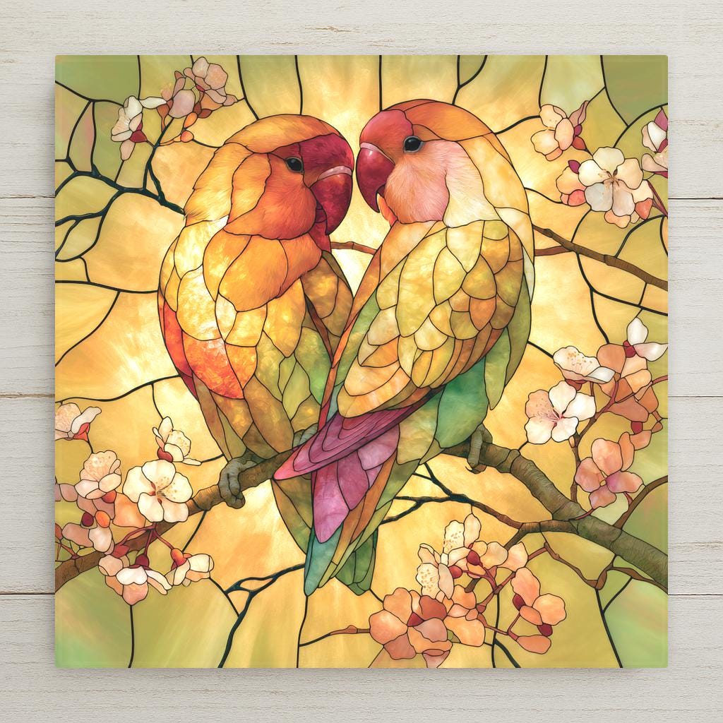 Stained glass style ceramic tile of two lovebirds with rosy faces and gold and green feathers perched close together on a flowering branch in radiant golden light