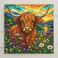 Stained glass style ceramic tile of a shaggy highland cow standing in a wildflower meadow before a sunset loch in the Scottish Highlands