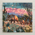 Stained glass style ceramic art tile of a javelina mother and two young trotting through sonoran desert prickly pear and cholla under a rising moon and pink mountain sunset