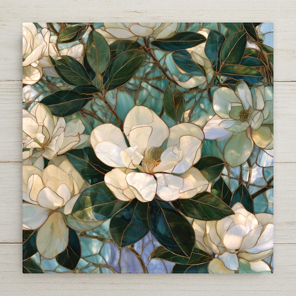 Stained glass style ceramic art tile of southern magnolia blossoms, creamy white petals with gold leading and deep green leaves against soft teal and periwinkle glass