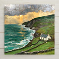 Stained glass style ceramic art tile of the irish coast, white cottage and stone-walled green pastures with sheep above teal atlantic surf and sea cliffs, storm clouds breaking to golden sun