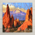 Stained glass style ceramic art tile of red rock spires at garden of the gods framing snow capped pikes peak, blue sky and golden clouds in mosaic glass panels