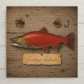 Sockeye salmon ceramic tile art in vintage specimen plate style with a hand-painted-style red and green spawning sockeye, tied fly fishing flies and an aged paper name label on weathered barnwood