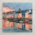Alcohol ink style ceramic art tile of Dingle Harbor in Ireland at dusk, colorful row houses with glowing windows reflected in calm water, fishing boats moored along the quay.