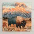 Alcohol ink style ceramic art tile of a lone bison in golden autumn grass below the Teton mountain range at sunset, peaks glowing peach with fine gold veining along every ridge.