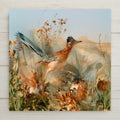 Alcohol ink style ceramic art tile of a greater roadrunner striding through dry desert grass, blue tail raised, with orange marigolds, blue lupine and agave in the foreground and a distant mesa under a pale sky